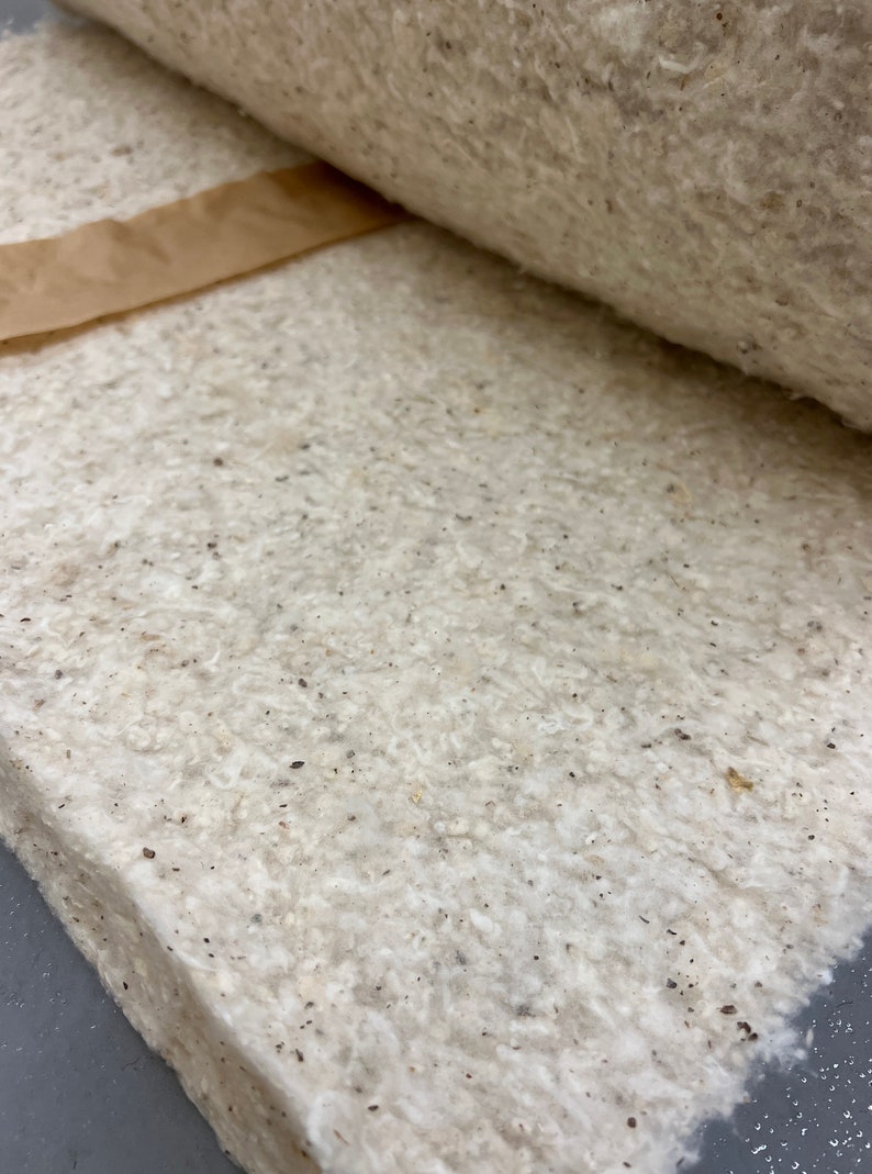 K&ouml;nnte beinhalten: Nahaufnahme eines wei&szlig;en, strukturierten, handgefertigten Papierblattes mit braunen Flecken. Das Papier ist in der Mitte gefaltet und hat ein braunes Papierklebeband am oberen Rand.