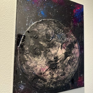 May include: A black and white textured painting of a planet with craters against a dark blue and purple galaxy background.