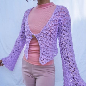 May include: A lavender crochet cardigan with a button closure and bell sleeves.