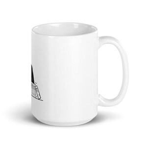 May include: White ceramic coffee mug with a black and white illustration of a person with their head down, reading a stack of books.
