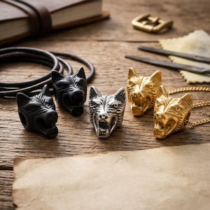 May include: A collection of wolf head beads and pendants in black, silver, and gold tones. The set includes two matte black wolf head beads, one polished silver wolf head bead, and two gold-toned wolf head pendants, one of which is attached to a chain.