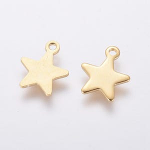 May include: Two gold-colored star charms with a loop at the top for hanging. The charms have a smooth, polished finish and a five-pointed star design. These charms are suitable for jewelry making or craft projects.