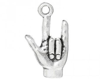 Puede incluir: Un charm de color plateado con forma de mano haciendo el signo "Te quiero". El charm tiene un lazo en la parte superior para sujetarlo a un collar o pulsera. La mano está detallada con líneas y texturas.