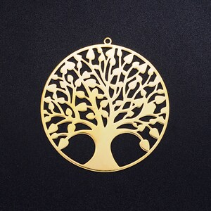 May include: A gold-colored metal pendant in the shape of a tree of life. The pendant is intricately designed with a circular outline and a detailed tree with branches and leaves.
