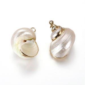 Peut inclure: Deux breloques en forme de coquillage nacré, avec une bordure dorée et une petite boucle pour suspendre. Les coquillages ont un design en spirale et une forme naturelle, idéale pour la création de bijoux ou les créations sur le thème marin.
