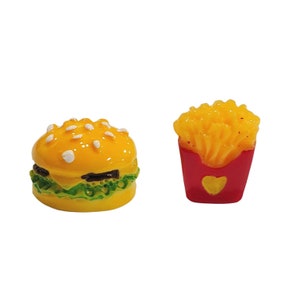 May include: A miniature yellow plastic hamburger with a green lettuce bun and a red plastic container of yellow french fries.