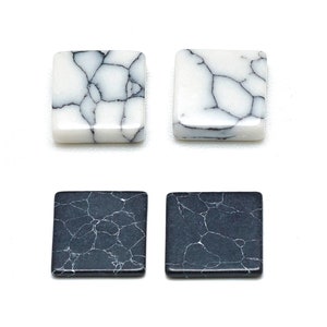 May include: Four square-shaped tiles with a marbled pattern. Two tiles are white with black veins, and two tiles are black with white veins.