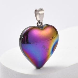 May include: A heart-shaped pendant with a polished, iridescent surface displaying a spectrum of colors, including purple, blue, and gold. The pendant has a silver-colored bail for attaching to a chain. The heart is approximately 1 inch wide.