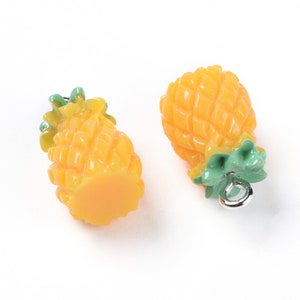 May include: Two yellow pineapple charms with green leaves and silver jump rings. The charms are made of plastic and are about 1 inch tall.