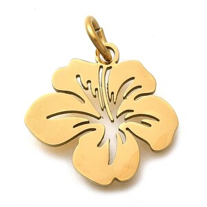 Puede incluir: Un colgante de flor de hibisco de color dorado con un lazo para colgar. El colgante tiene un dise&ntilde;o recortado detallado en el centro y p&eacute;talos lisos. La flor es un s&iacute;mbolo de belleza y se asocia a lugares tropicales.