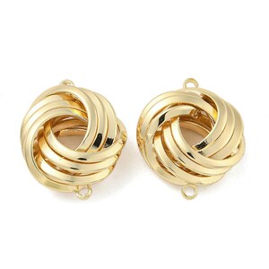 May include: Two gold-colored, knot-shaped earring components. Each component has a loop at the top and bottom for attachment. The earrings have a shiny, metallic finish and a three-dimensional design.