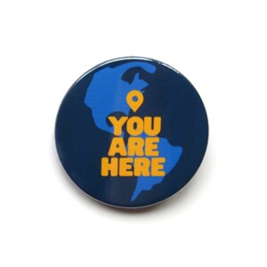 May include: A blue and yellow button with a world map and the text "YOU ARE HERE" on it.