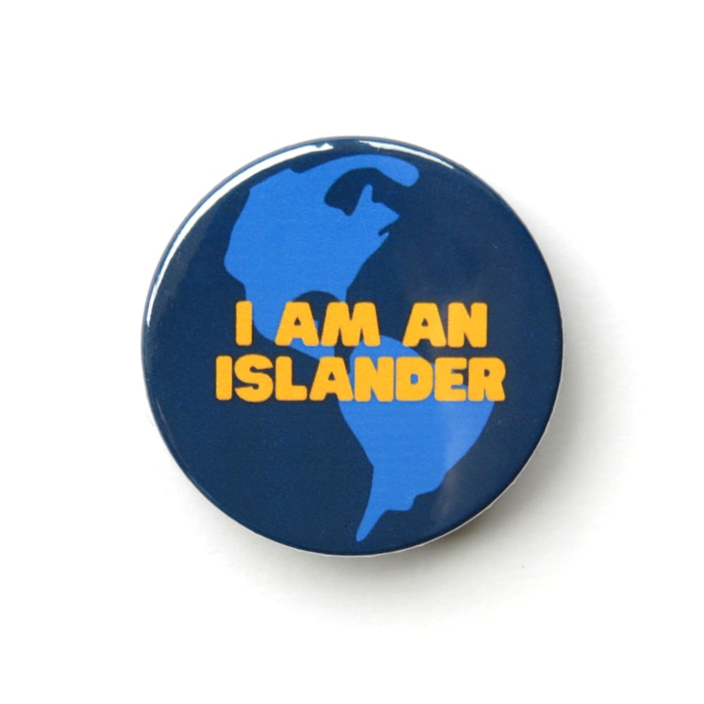May include: A blue and navy blue button with a stylized image of the Earth and the text "I AM AN ISLANDER" in yellow.