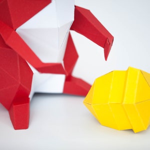 May include: A red and white origami figure with a yellow origami sphere in front of it. The figure appears to be reaching out to the sphere.