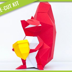 May include: A pre-cut kit for a 3D papercraft squirrel holding a yellow acorn. The squirrel is red and white, and the acorn is yellow.