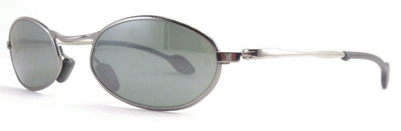 May include: Oval-shaped sunglasses with a silver metal frame and dark green lenses. The sunglasses have a sleek, modern design with a curved bridge and temples. The nose pads are gray. The overall look is minimalist and stylish.