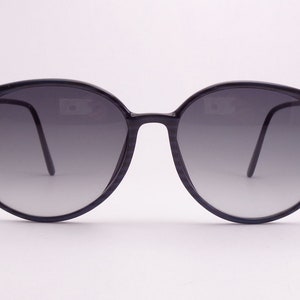 May include: A pair of round, black sunglasses with gradient grey lenses.