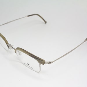 May include: A pair of silver and brown eyeglasses with a half-rim frame. The brand name "R.  RODENSTOCK" is printed on the right temple.