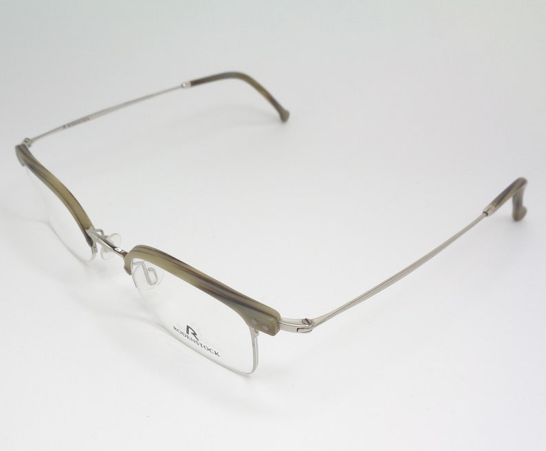 May include: A pair of silver and brown eyeglasses with a half-rim frame. The brand name "R.  RODENSTOCK" is printed on the right temple.