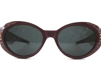 May include: Burgundy oval sunglasses with gold accents and dark lenses.