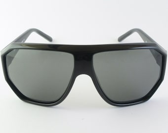 May include: Black sunglasses with a geometric frame and dark gray lenses.