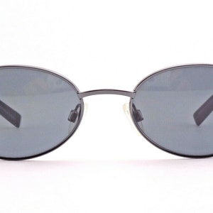 May include: A pair of oval-shaped sunglasses with a dark gray frame and lenses.