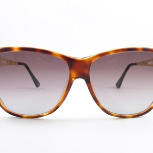May include: Tortoise shell cat eye sunglasses with rhinestones on the temples and gradient brown lenses.