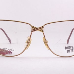 May include: Gold-plated eyeglasses with a cat-eye frame and clear lenses. The brand name "DOLCE VITA" is printed on the right lens.