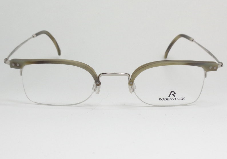 May include: Silver and tortoise shell eyeglasses with clear lenses. The brand name "R RODENSTOCK" is printed on the right lens.