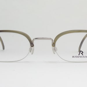 May include: Silver and tortoise shell eyeglasses with clear lenses. The brand name "RODENSTOCK" is printed on the right lens.