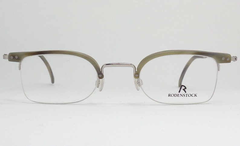 May include: Silver and tortoise shell eyeglasses with clear lenses. The brand name "RODENSTOCK" is printed on the right lens.
