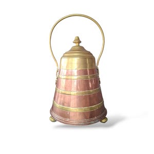 May include: A copper and brass container with a handle. The container has a conical shape with horizontal brass bands. The lid and handle are brass. The container rests on three small brass feet. The overall design is vintage.