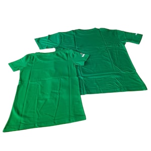 May include: Two green t-shirts, one smaller than the other, are displayed against a white background. The shirts are made of a smooth fabric and have short sleeves. The smaller shirt is in the foreground, with the larger shirt behind it.