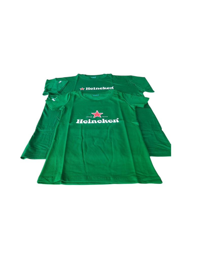 May include: Two green t-shirts with the Heineken logo printed on the front. The logo features a red star and the brand name in white. The shirts are short-sleeved and made of a soft material.