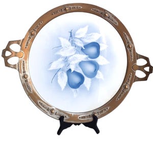 May include: A vintage oval serving tray with a blue and white porcelain insert featuring a hand-painted design of pears on a branch. The tray has a gold-toned metal frame with decorative accents and two ornate handles.