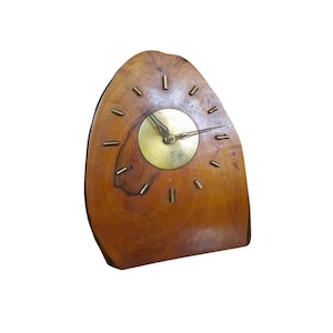 May include: A wooden clock with a brass face and hands. The clock is shaped like a tree stump and has a natural wood finish.