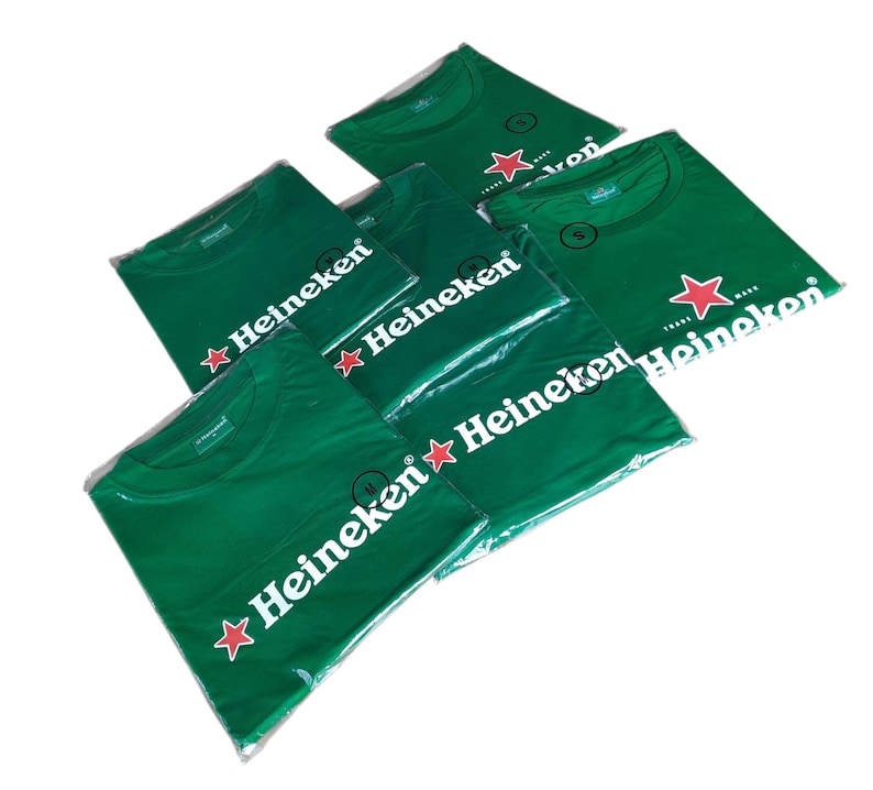 May include: Several green t-shirts, each packaged in clear plastic. The shirts feature the Heineken logo in white with a red star. The shirts are a solid green color.
