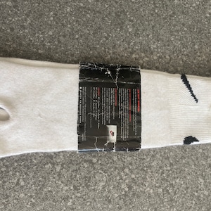 Pu&ograve; includere: Calze tabi bianche con un logo Swoosh nero e un'etichetta che recita "Air Rift Sneakers".