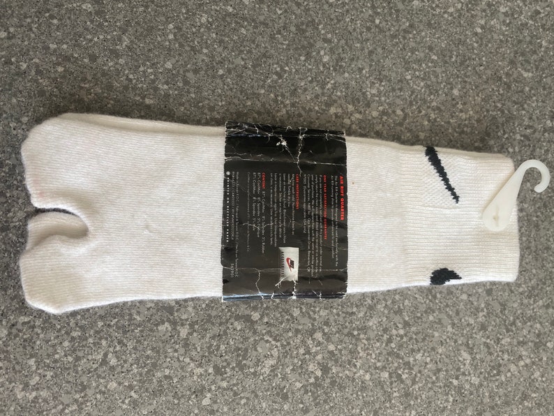 Pu&ograve; includere: Calze tabi bianche con un logo Swoosh nero e un'etichetta che recita "Air Rift Sneakers".