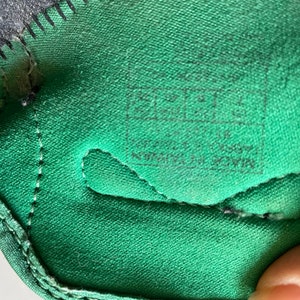 Pu&ograve; includere: Primo piano dell'interno di una scarpa verde con cuciture nere e un'etichetta nera che recita "MADE IN CHINA  ALL MATERIALS  ARTIFICIAL DOWN"