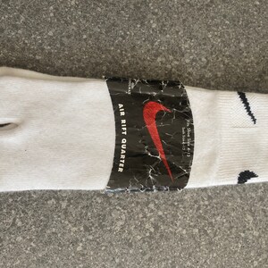 Pu&ograve; includere: Calzini tabi bianchi con un logo Nike swoosh nero e il testo "AIR RIFT QUARTER" sulla confezione. La confezione indica anche "Fit Shoe Size 4-13 Sock Size 13".