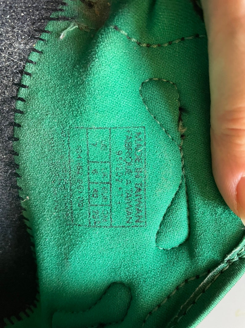 Pu&ograve; includere: Primo piano dell'interno di una scarpa verde con cuciture nere. La taglia della scarpa &egrave; stampata in nero su un'etichetta bianca: "US 7.5, UK 6.5, EUR 39, CM 24.5".