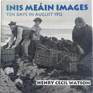 May include: A black and white photograph of three people standing on a rocky beach. The people are carrying wicker baskets. The photograph is titled "Inis Meáin Images Ten Days in August 1912" and is signed "Henry Cecil Watson".