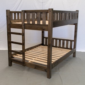 May include: A dark brown wooden bunk bed with a ladder on one side. The bed has a slatted headboard and footboard.
