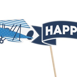 Puede incluir: Avi&oacute;n azul y blanco con una pancarta que dice "HAPPY" en un palo de madera.