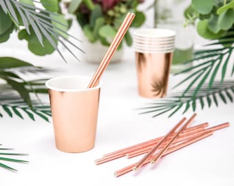 May include: Rose gold paper cups and straws. The cups have a metallic finish and the straws are striped.