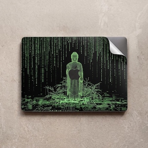May include: Laptop skin featuring a neon green Buddha statue holding an apple, set against a black background with a Matrix-style digital rain effect. The design includes green geometric lines and plant silhouettes.