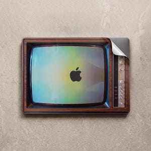Op de afbeelding: Een vintage houten televisie met een laptopscherm met het Apple-logo. De laptop is gedeeltelijk teruggeklapt en onthult het scherm. De televisie heeft een bruine lijst en zilveren bedieningsknoppen.