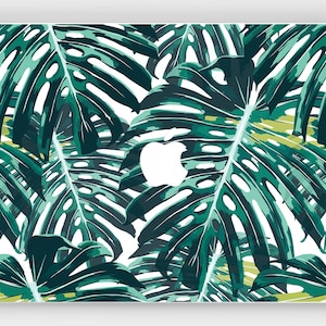 Könnte beinhalten: Eine Laptop-Haut mit einem tropischen Blatt-Muster in Grün- und Weißtönen. Das Design zeigt große, stilisierte Blätter auf weißem Hintergrund.