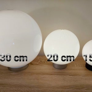 May include: Three white globe lamps of different sizes. The largest lamp is 30 inches in diameter, the middle lamp is 20 inches in diameter, and the smallest lamp is 15 inches in diameter.